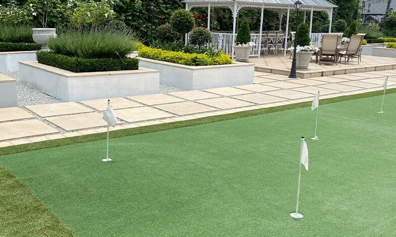 artificial grass putting green installed in back garden with flags