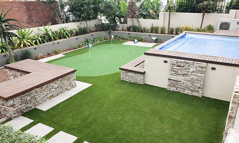 putting green with artificial grass installed near pool